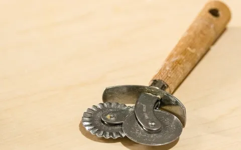 Rotella tagliapasta con la ruota liscia e quella dentata, appoggiata sul tagliere