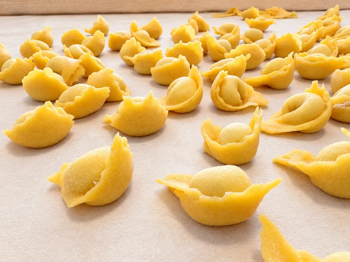Cappelletti appena chiusi a mano, in fila sul tagliere infarinato ad asciugare