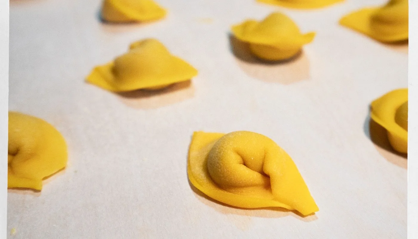 Cappelletti crudi appena chiusi, con la punta alzata, sul piano infarinato
