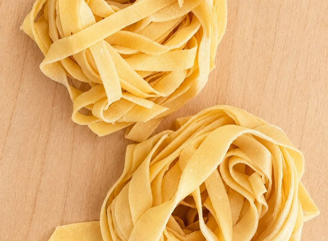 Due nidi di tagliatelle all'uovo ad asciugare sul tagliere di legno