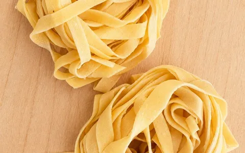Due nidi di tagliatelle all'uovo ad asciugare sul tagliere di legno