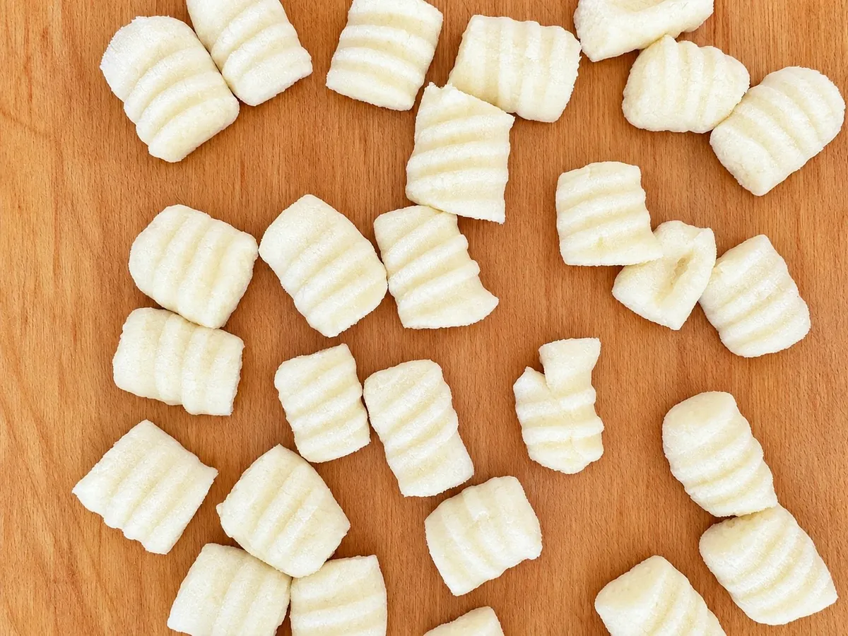 Gnocchi di patate rigati sulla forchetta, sparsi sul tagliere di legno