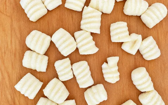 Gnocchi di patate rigati sulla forchetta, sparsi sul tagliere di legno