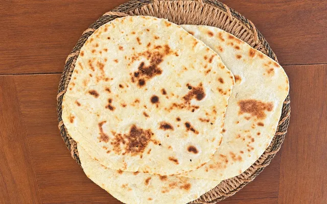 Due piadine appena cotte sul cestino di vimini, con le macchie brune della cottura