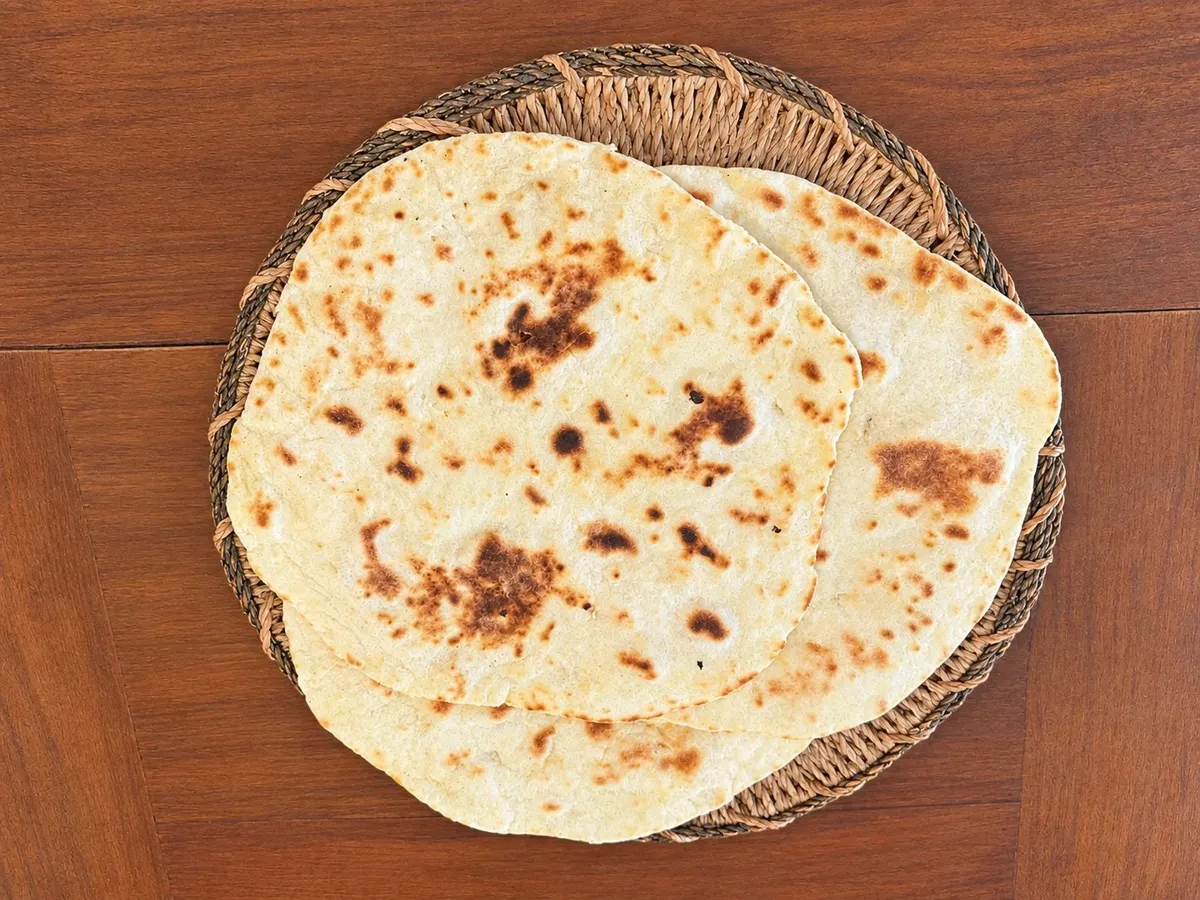 Due piadine appena cotte sul cestino di vimini, con le macchie brune della cottura