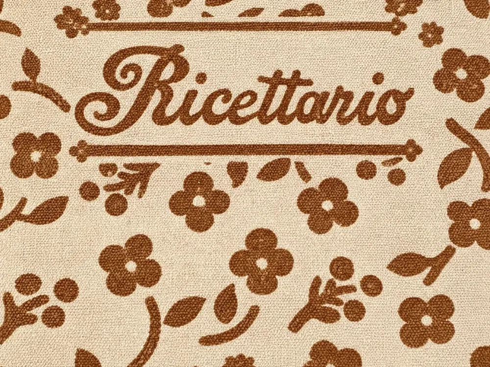 Copertina in tela del ricettario, con la scritta Ricettario in corsivo fra i fiorellini stampati